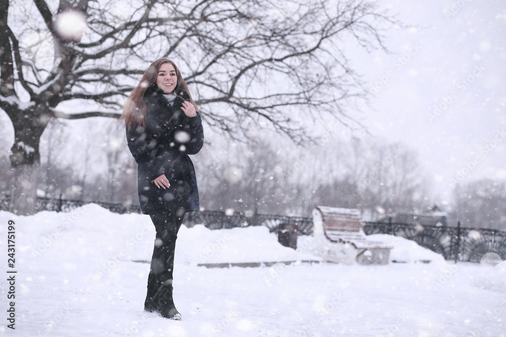 Girl in a winter park in snowfall