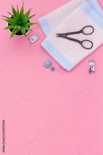 Woman hobby. Set for tailor shop with thread, scissors, fabric on pink background top view copy space