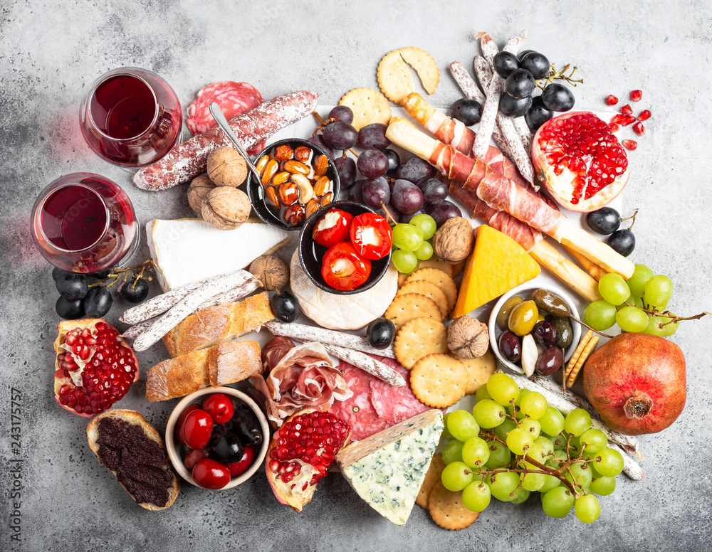 Festive gourmet mix of snacks and appetizers, cheese, meat, olives, bread,  fruit, canapés, wine in glasses.