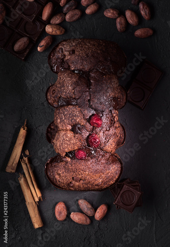 aerial shot of uncut chocolate cake, chocolate pieces and cocoa beans on rough gray background photo