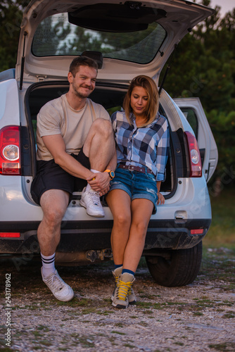 Young couple sitting on the back of a off road vehicle and enjoying the view from inside the all terrain vehicle at sunset. © qunica.com