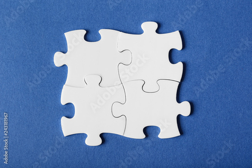 Four fastened puzzles of different colors on blue background