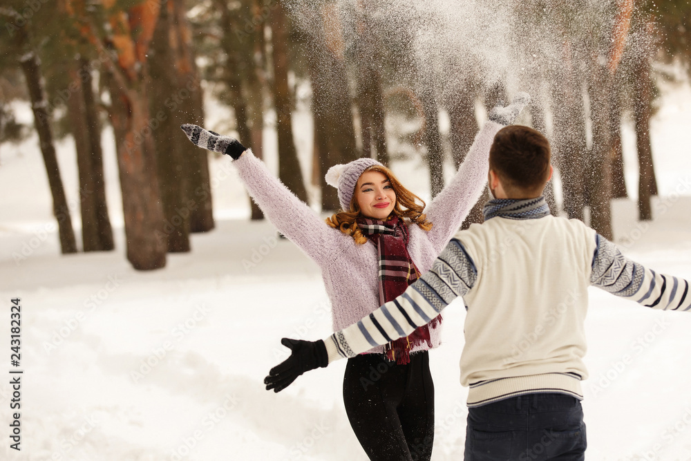 Winter, couple in love. Young man and woman having fun with white snow in  snowy forest. Romantic couple in winter wear enjoying snowfall. Love story  in the winter forest фотография Stock |