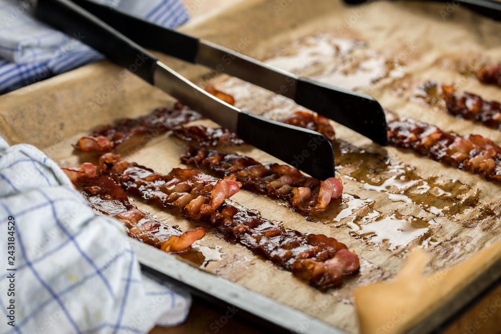 Knusprig gebratene Bacon Speck Scheiben aus dem Ofen auf Backblech mit Backpapier mit