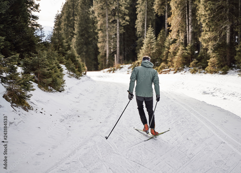 Caucasian man enjoying his free time cross country skiing in the woods, covered with snow