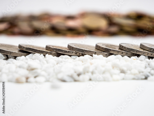 Image of line of two Euro coins on white little stones close up
