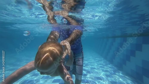 Happy smiling toddler is diving under water with father