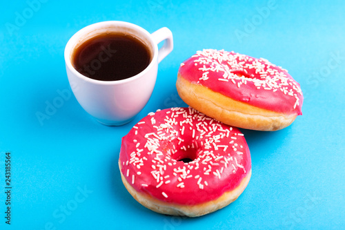 Two delicious pink donuts with sprinkle and cup of coffee