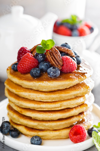 Stack of fluffy pancakes with fresh berries and pecan nuts