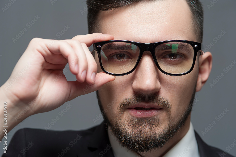 Close-up Serious businessman in formal suit and glasses looks at the camera on gray background. Place for text Close-up Serious businessman in formal suit and glasses looks at the camera on gray background. Place for text