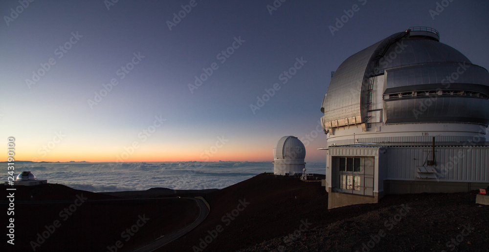 Sunset at Mauna Kea Hawaii with view of observatories and a sea of clouds