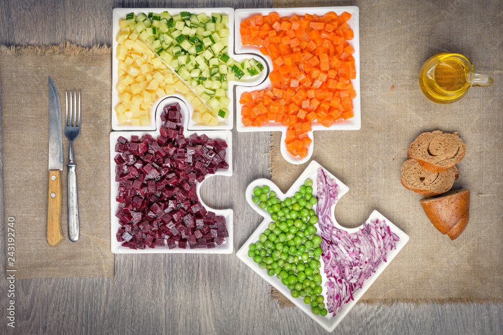 Assemble jigsaw puzzles for a healthy diet. Raw vegetables carrots, peas, onions, cucumber, potatoes, beets cut into cubes lie on plates that are collected in puzzles.