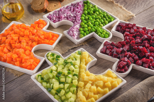 Raw vegetables carrots, peas, onions, cucumber, potatoes, beets cut into cubes lie on plates that are collected in puzzles.Healthy eating concept.