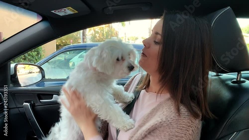 Happy woman holding kissing dog in car in love photo