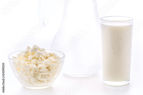 Fresh milk in a glass poured from a jug with a bowl of cottage cheese. Dairy products in the morning for breakfast are very healthy.