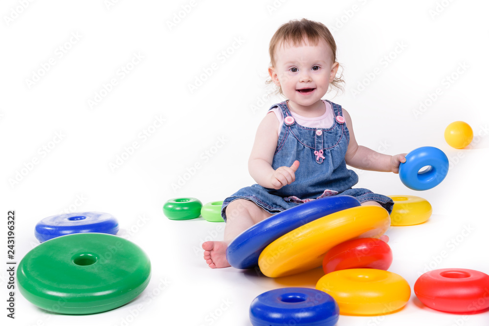 Cute little girl, enthusiastically playing in colorful pyramid, isolated on white background. Cute little girl, enthusiastically playing in colorful pyramid, isolated on white background.