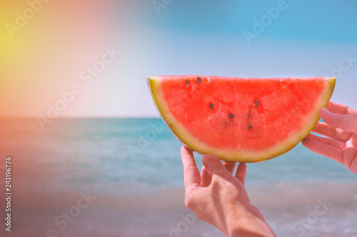 Watermelon, juicy slice in the hands of a woman with over the sea, in the rays of a sunny sunset. Diet of tropical fruits..