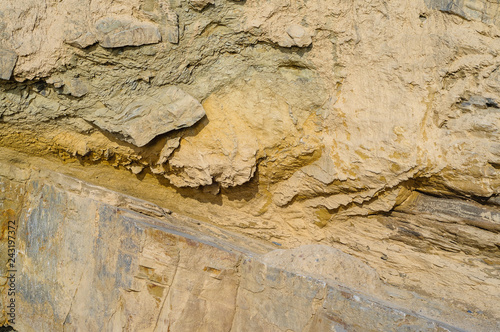 Surface of the rock with a granite stone texture. Designer background for interiors. Stone surface of a yellow texture close-up.