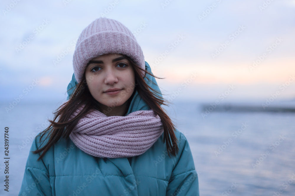 portrait of pensive young cute woman in warm hat and scarf near the sea in the winter day portrait of pensive young cute woman in warm hat and scarf near the sea in the winter day