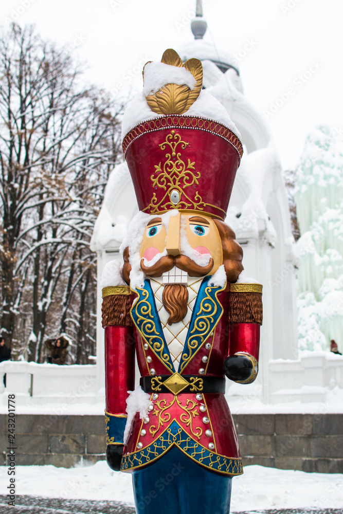 Statue in the form of a snow-covered toy soldier in a city park in winter