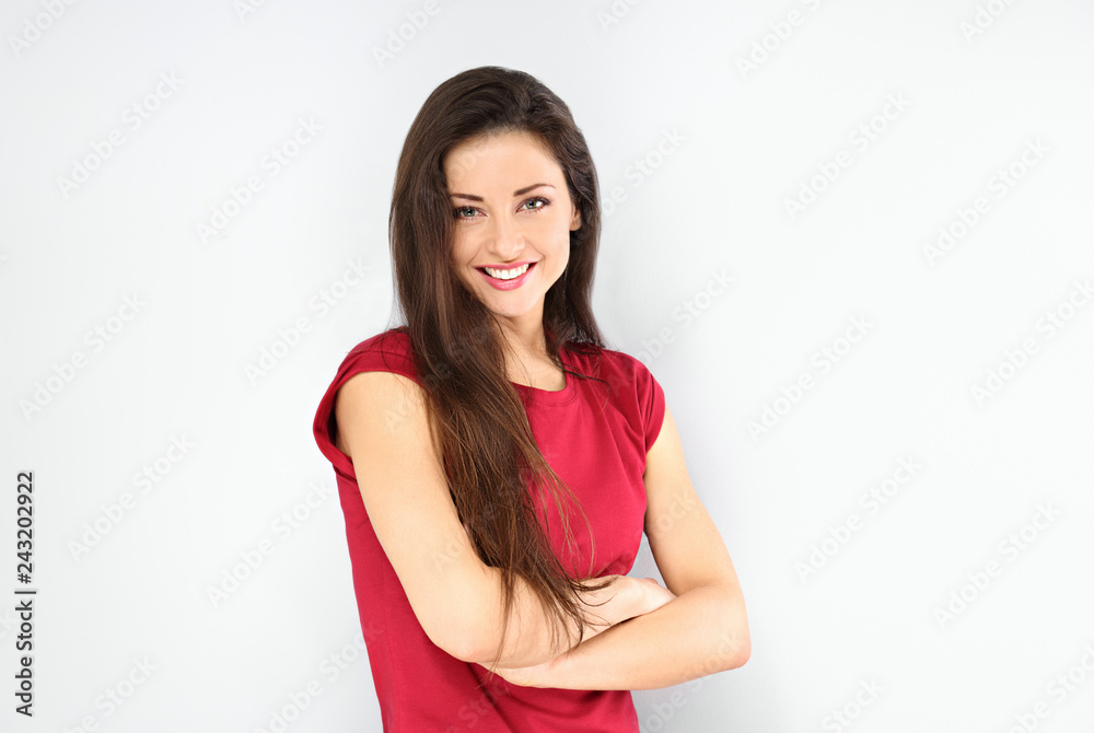 Beautiful positive toothy smiling woman with folded arms looking happy in casual red shirt on blue background Beautiful positive toothy smiling woman with folded arms looking happy in casual red shirt on blue background