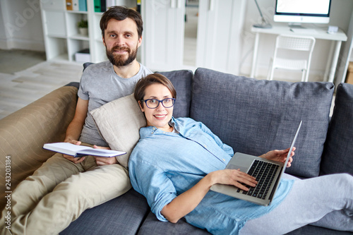 Restful young man and woman in casualwear lying on sofa and enjoying leisure at home