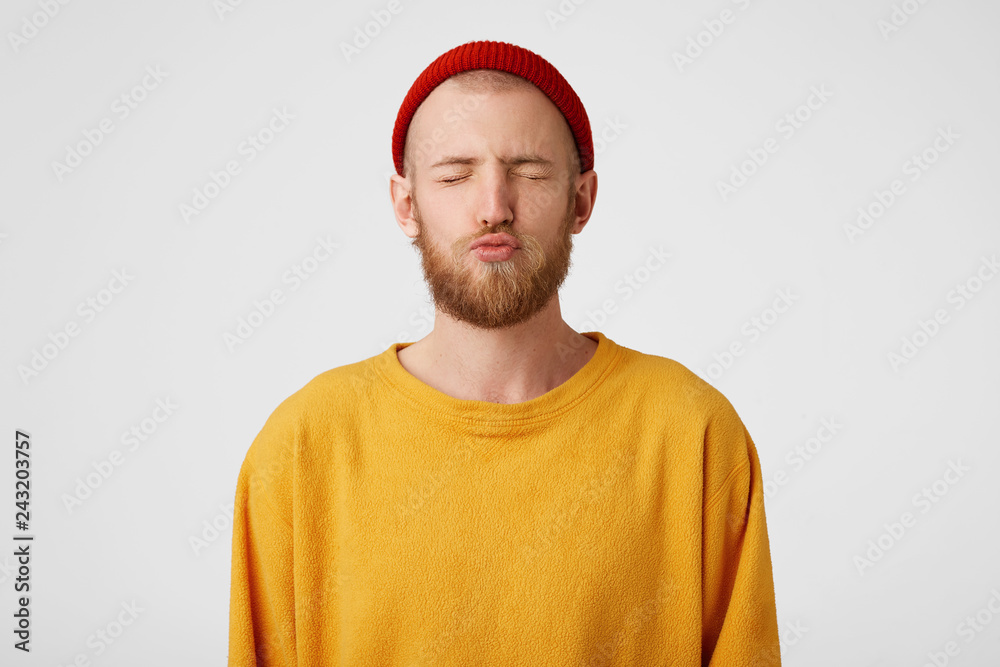 Young attractive charming bearded guy sends a air kiss standing eyes closed isolated on white background. Young attractive charming bearded guy sends a air kiss standing eyes closed isolated on white background.