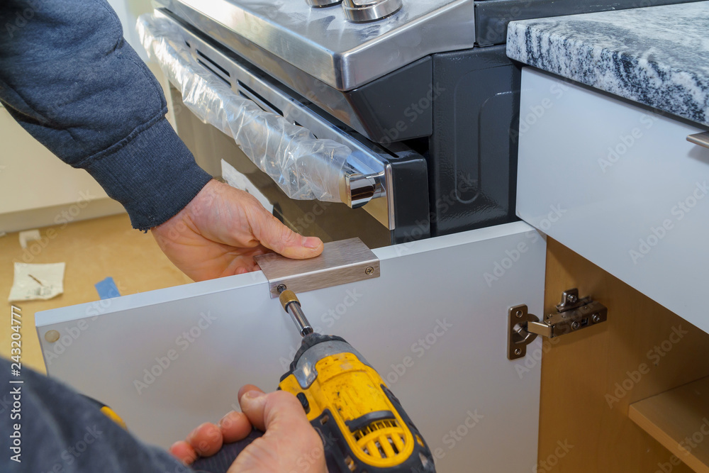 Installation of door handles on kitchen cabinets with a screwdriver