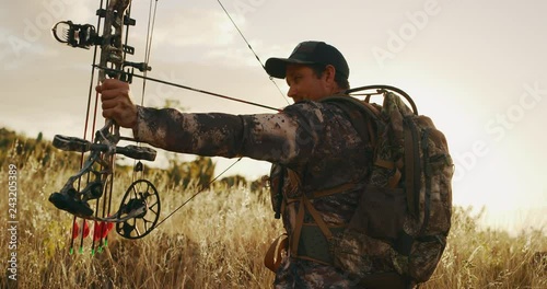 Orbit shot of experienced bowhunter drawing an arrow in his compound bow photo