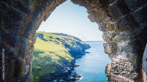 Billede på lærred View through the ruins of Tintagel castle of British west landscape coastline, shore for summer holidays