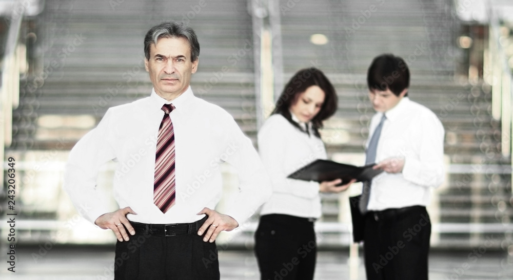 Portrait of a smiling handsome businessman. working team communicating at background Portrait of a smiling handsome businessman. working team communicating at background