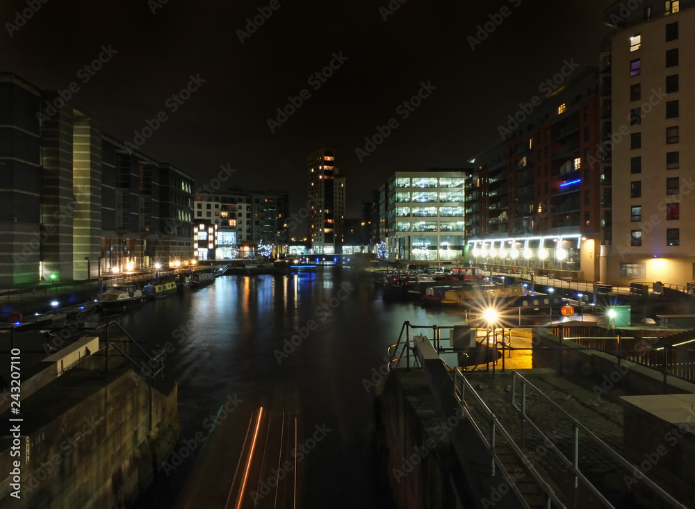 cityscape view of clarence dock in leeds at night showing the lock gates and water surrounded by buildings
