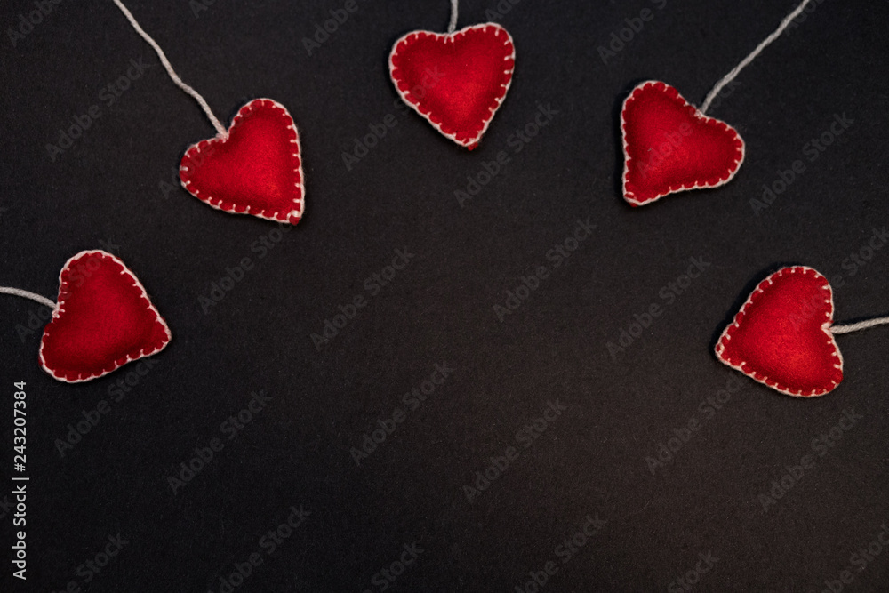 Obraz premium A row of red hearts from felt. Background for congratulations on Valentine's Day. Background for sale. Black lettering paper.