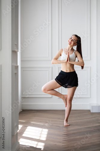 Happy and beautiful woman do yoga exercises at home.