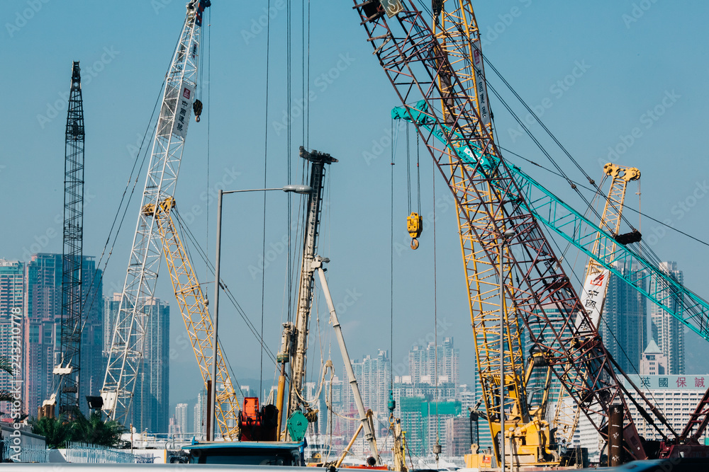 Harbor cranes infront of city buildings in sunny day