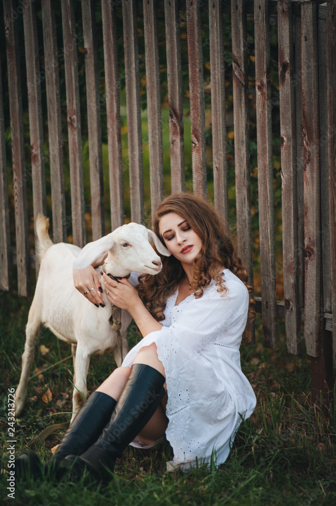 .A girl in a white dress walks with a goat in nature. .A girl in a white dress walks with a goat in nature.