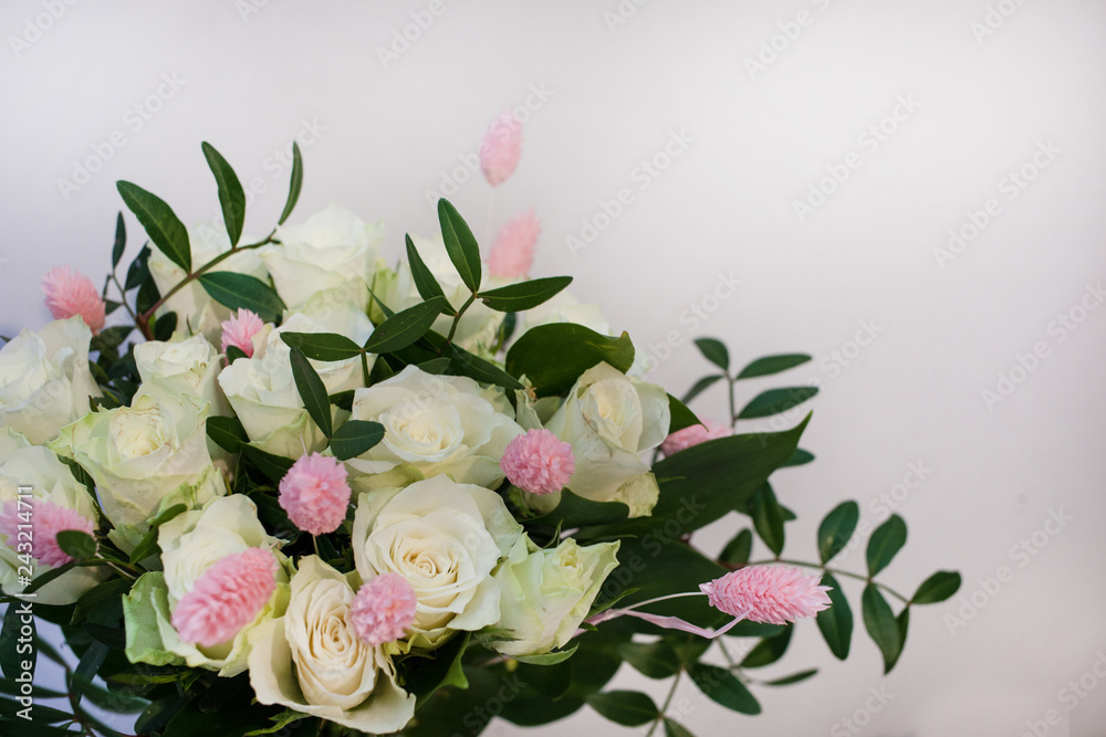 bouquet of white roses with pink lagurus against the background of a white wall. Copy space. International Women's Day or St. Valentine's Day