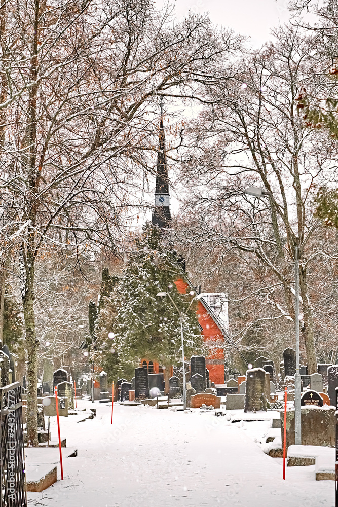 Fototapeta premium Porvoo, Finland - old town cemetery grave yard with Finnish Kirche church with winter snow