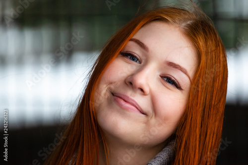 Photos portrait of a young blue-eyed smiling girl with bright red hair