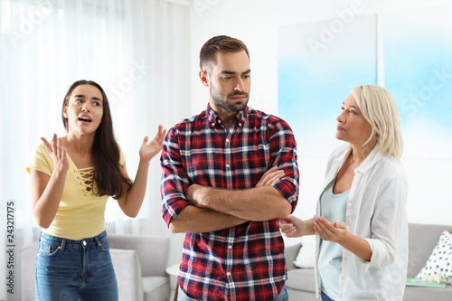 Konstfotografi Young man having argument with wife and mother-in-law at home