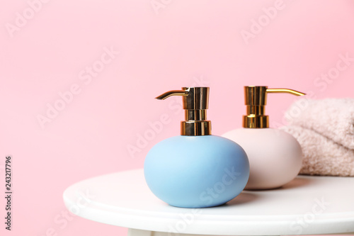 Stylish soap dispensers on table against color background. Space for text