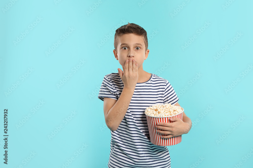 Fototapeta premium Emotional boy with popcorn during cinema show on color background