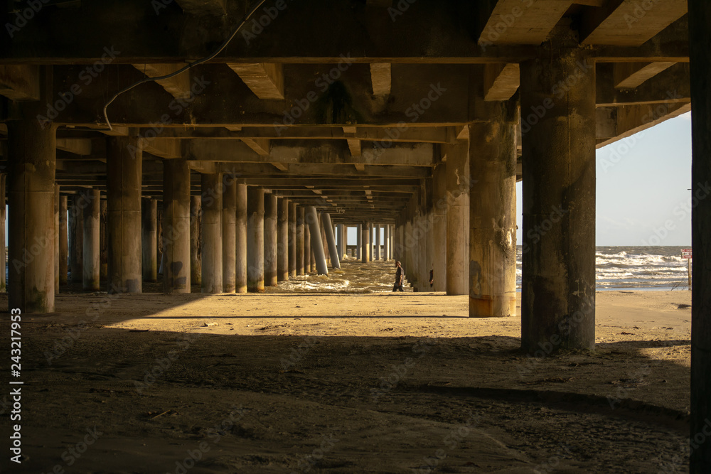 Under the pier at the beach in the shadows
