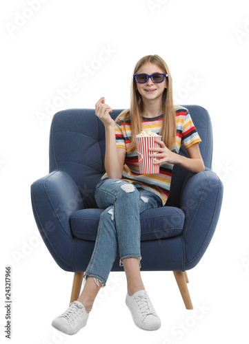 Teenage girl with 3D glasses and popcorn sitting in armchair during cinema show on white background