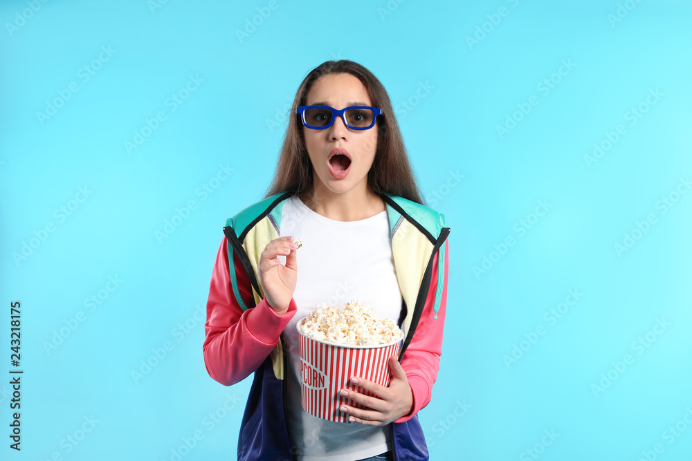 Naklejka premium Emotional woman with 3D glasses and popcorn during cinema show on color background