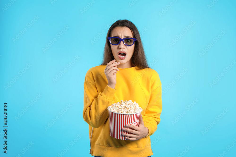 Fototapeta premium Emotional woman with 3D glasses and popcorn during cinema show on color background