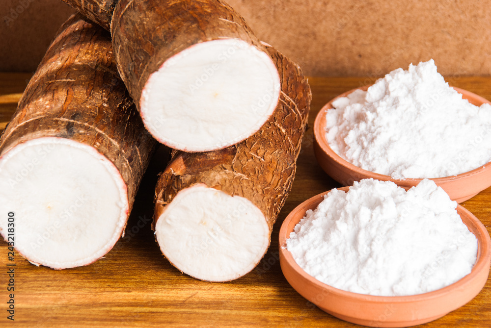 Fototapeta premium Raw cassava tuber on wooden background - Manihot esculenta