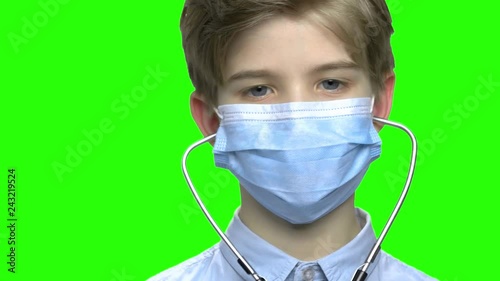 Close up child boy wear medical protective mask and stethoscope. Green hromakey background for keying. photo