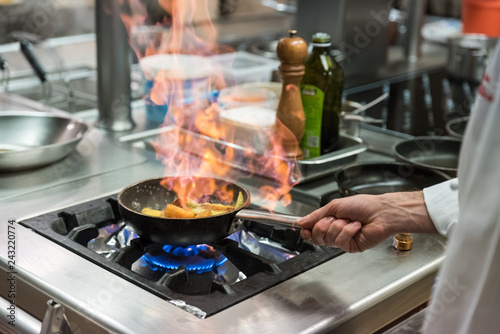 Fotografie cuoco cucina in padella con fiamma alta