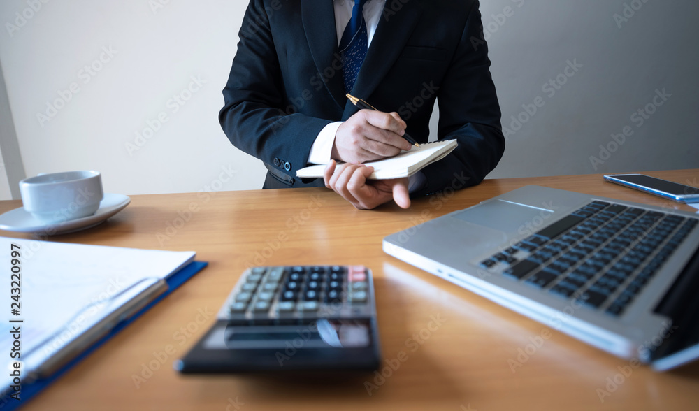 Businessman hand using pen writeing on book in office Businessman hand using pen writeing on book in office